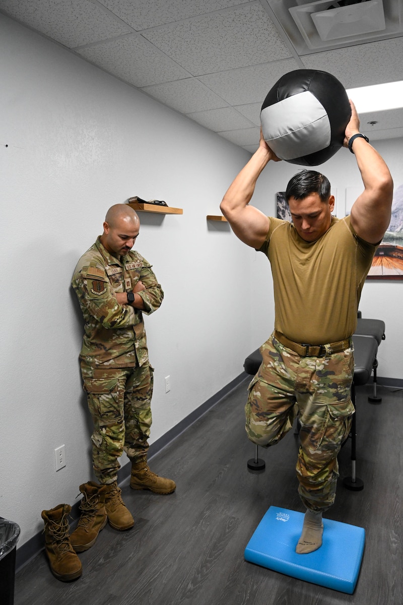 U.S. Air Force Staff Sgt. Brandon Gonzales, 97th Security Forces Squadron noncommissioned officer in charge of electric security systems, prepares to throw a medicine ball during a physical therapy session with Capt. Chase Leavy, 97th Operation Support Team physical therapist, at Altus Air Force Base, Oklahoma, Aug. 14, 2024. Medicine balls are used for strength training and rehabilitation. (U.S. Air Force photo by Senior Airman Miyah Gray)