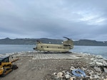 An Alaska Army National Guard CH-47 Chinook lands for the first time on Little Diomede, Alaska, with Big Diomede, Russia, visible in the background. The unit supported Operation Polar Dagger, a joint special operations mission across the Alaskan Arctic.