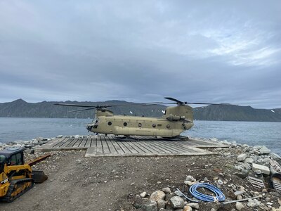 An Alaska Army National Guard CH-47 Chinook lands for the first time on Little Diomede, Alaska, with Big Diomede, Russia, visible in the background. The unit supported Operation Polar Dagger, a joint special operations mission across the Alaskan Arctic.