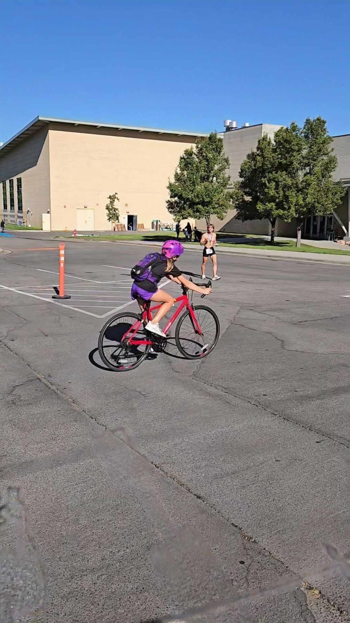 A girl rides a bick across a parking lot