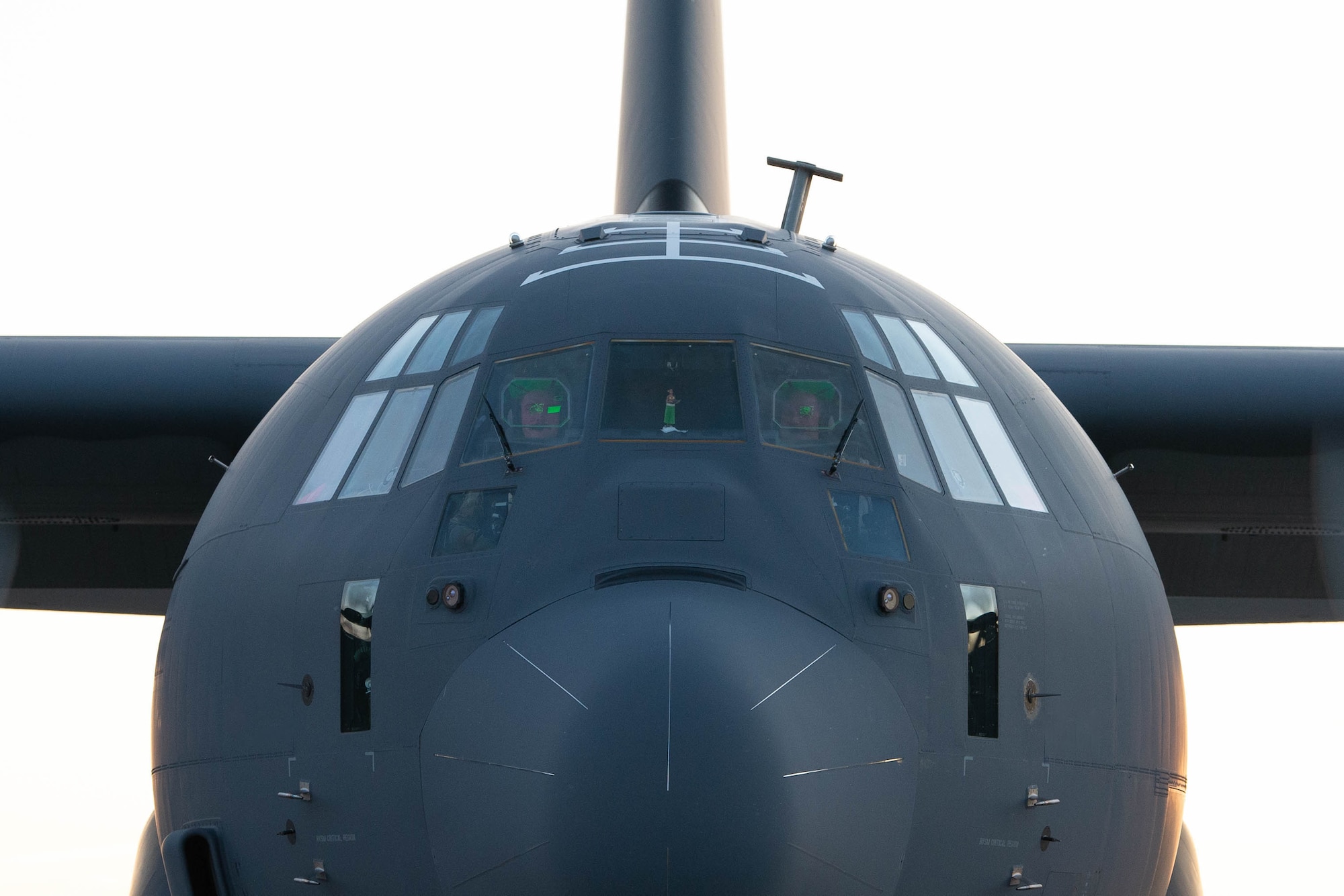 A military cargo aircraft taxis on a dirt air strip.