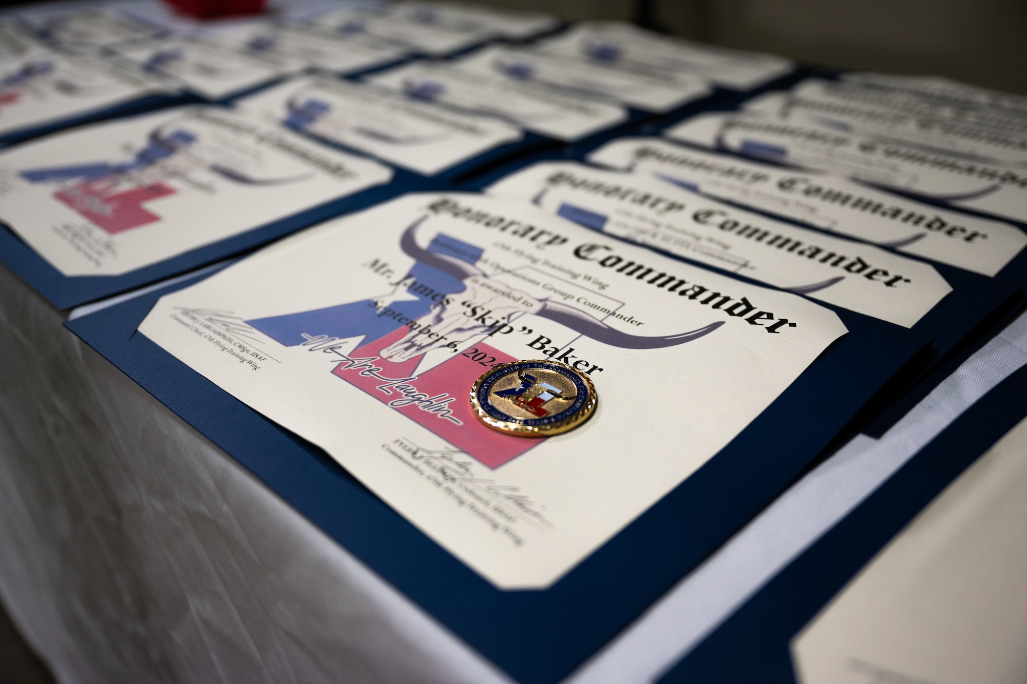 A certificate and challenge coin is presented to each honorary commander of class 2024- 2026 at the honorary commander ceremony at Laughlin Air Force Base, Texas Sept. 6, 2024. The Honorary commander program looks to bring local community leaders and base personnel closer together, fostering the close relationship between Del Rio and Laughlin. (U.S. Air Force photo by Airman 1st Class Harrison Sullivan)