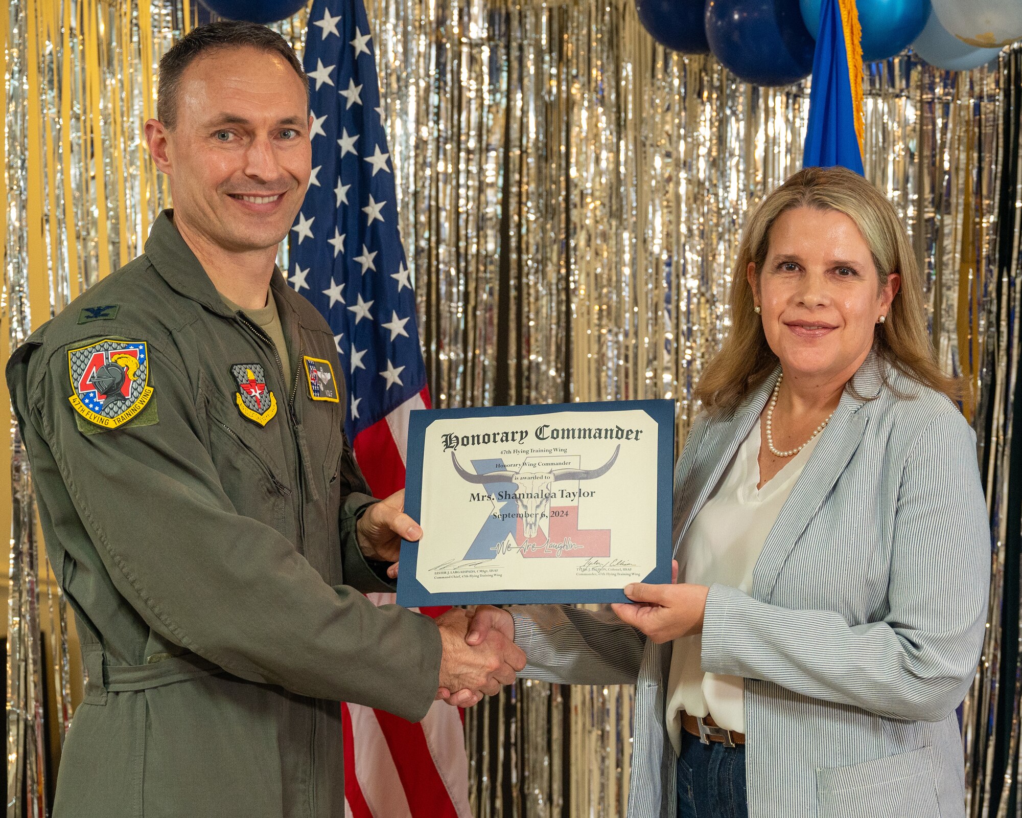 An honorary commander accepts their certificate from their commander at the honorary commander induction ceremony at Laughlin Air Force Base, Texas, Sept. 6, 2024. The honorary commander program looks to bring local community leaders and base personnel closer together, fostering the close relationship between Del Rio and Laughlin. (U.S. Air Force photo by Staff Sgt. Nicholas Larsen)