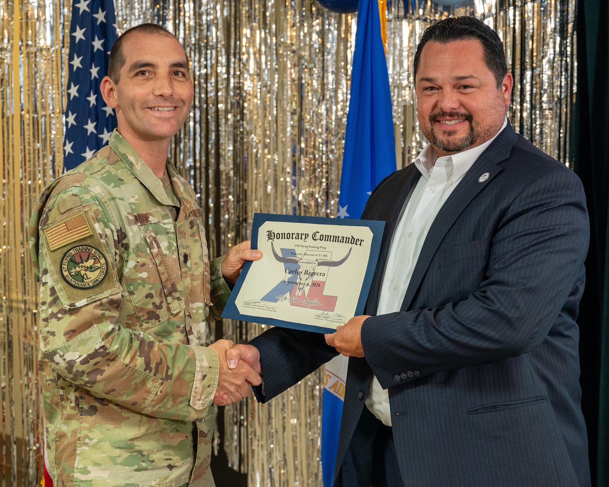 An honorary commander accepts their certificate from their commander at the honorary commander induction ceremony at Laughlin Air Force Base, Texas, Sept. 6, 2024. The honorary commander program looks to bring local community leaders and base personnel closer together, fostering the close relationship between Del Rio and Laughlin. (U.S. Air Force photo by Staff Sgt. Nicholas Larsen)