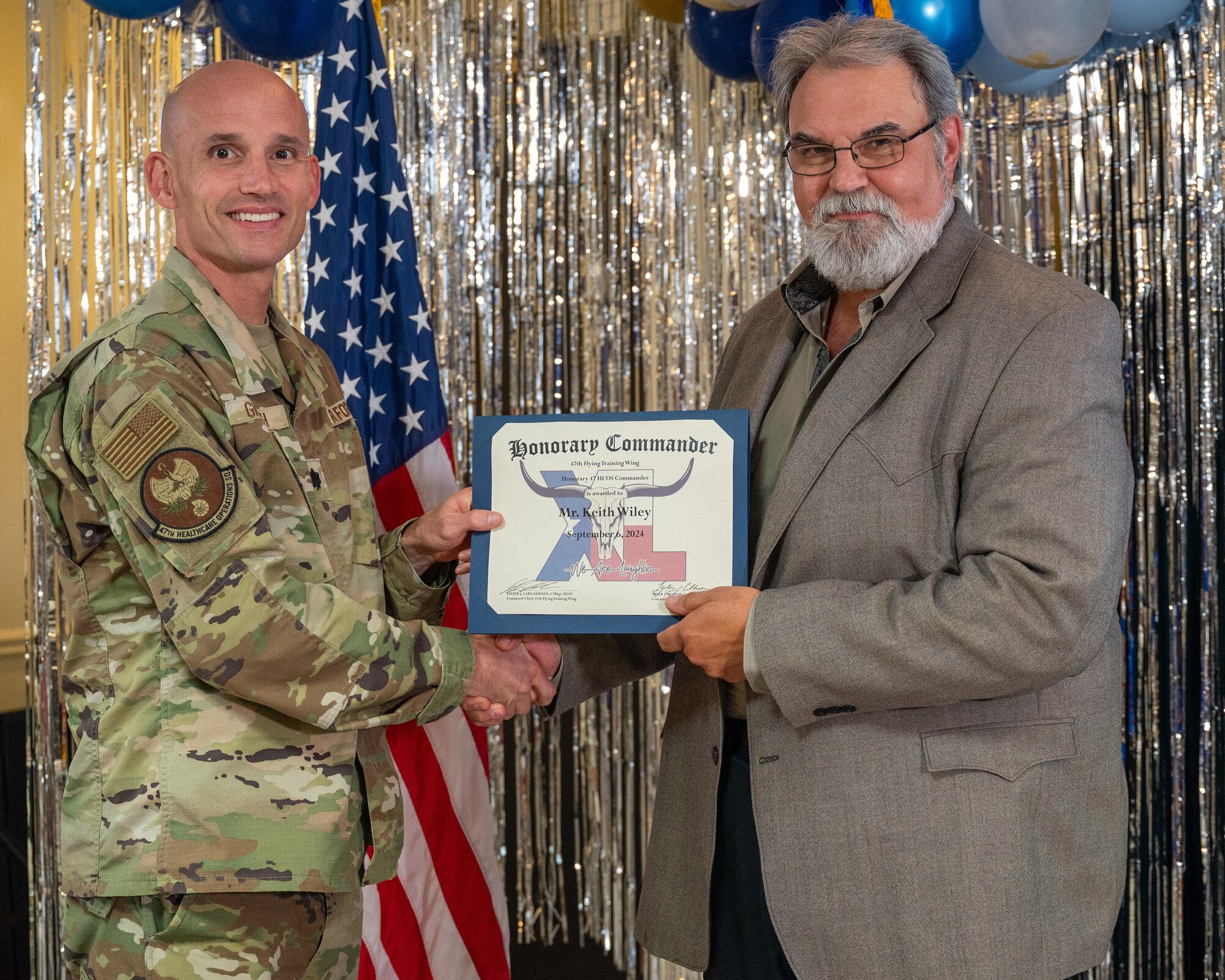 An honorary commander accepts their certificate from their commander at the honorary commander induction ceremony at Laughlin Air Force Base, Texas, Sept. 6, 2024. The honorary commander program looks to bring local community leaders and base personnel closer together, fostering the close relationship between Del Rio and Laughlin. (U.S. Air Force photo by Staff Sgt. Nicholas Larsen)