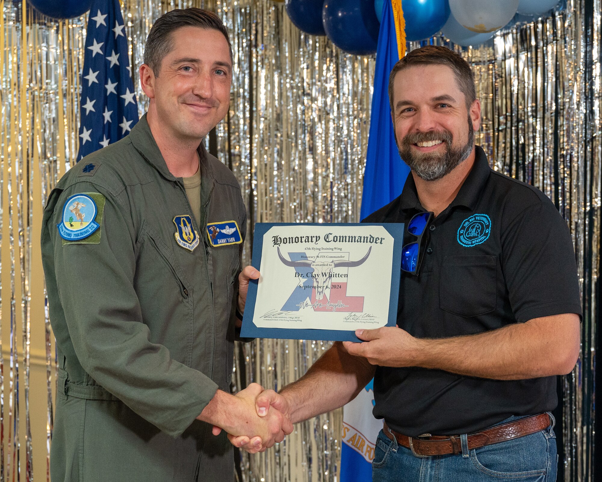 An honorary commander accepts their certificate from their commander at the honorary commander induction ceremony at Laughlin Air Force Base, Texas, Sept. 6, 2024. The honorary commander program looks to bring local community leaders and base personnel closer together, fostering the close relationship between Del Rio and Laughlin. (U.S. Air Force photo by Staff Sgt. Nicholas Larsen)