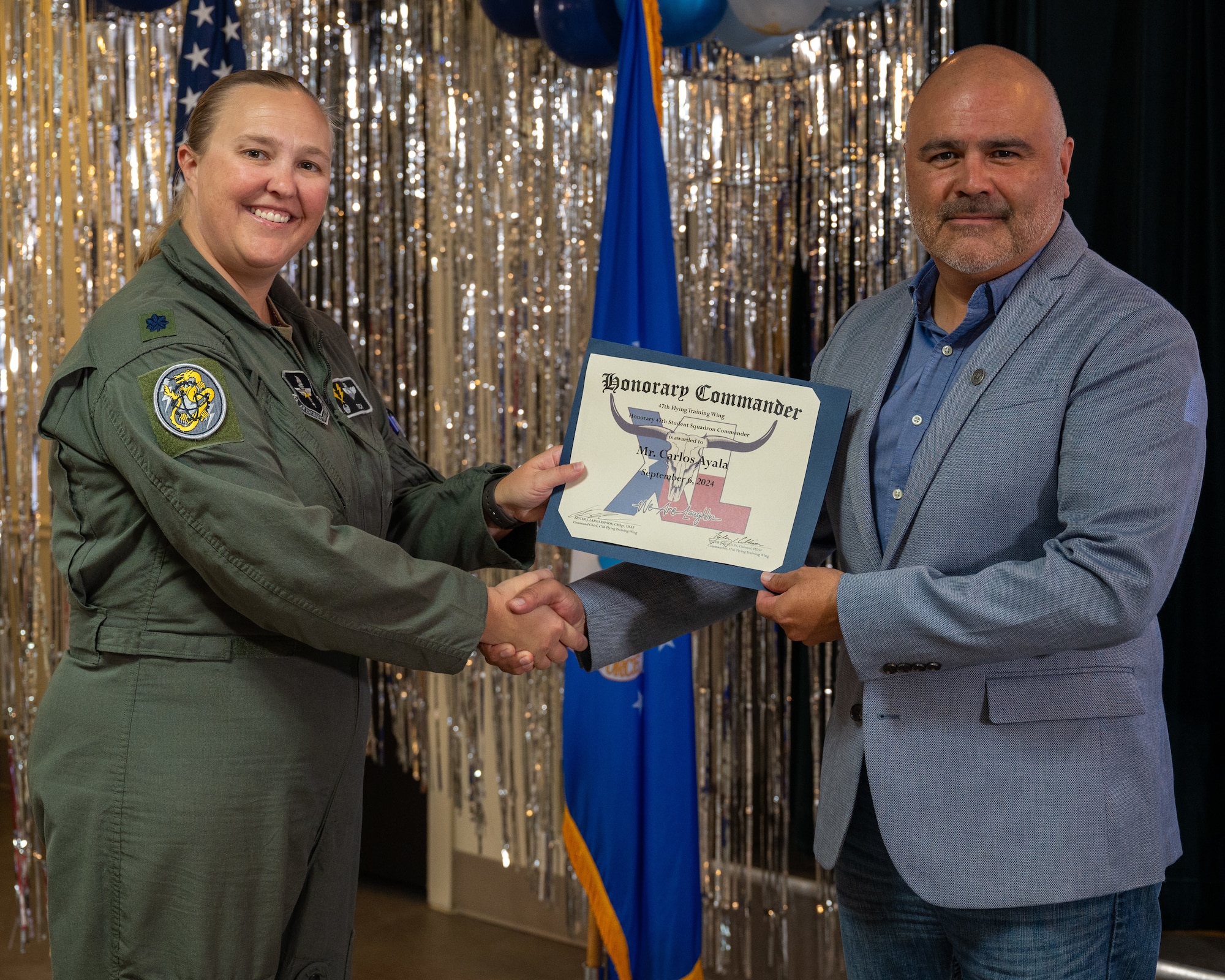An honorary commander accepts their certificate from their commander at the honorary commander induction ceremony at Laughlin Air Force Base, Texas, Sept. 6, 2024. The honorary commander program looks to bring local community leaders and base personnel closer together, fostering the close relationship between Del Rio and Laughlin. (U.S. Air Force photo by Staff Sgt. Nicholas Larsen)
