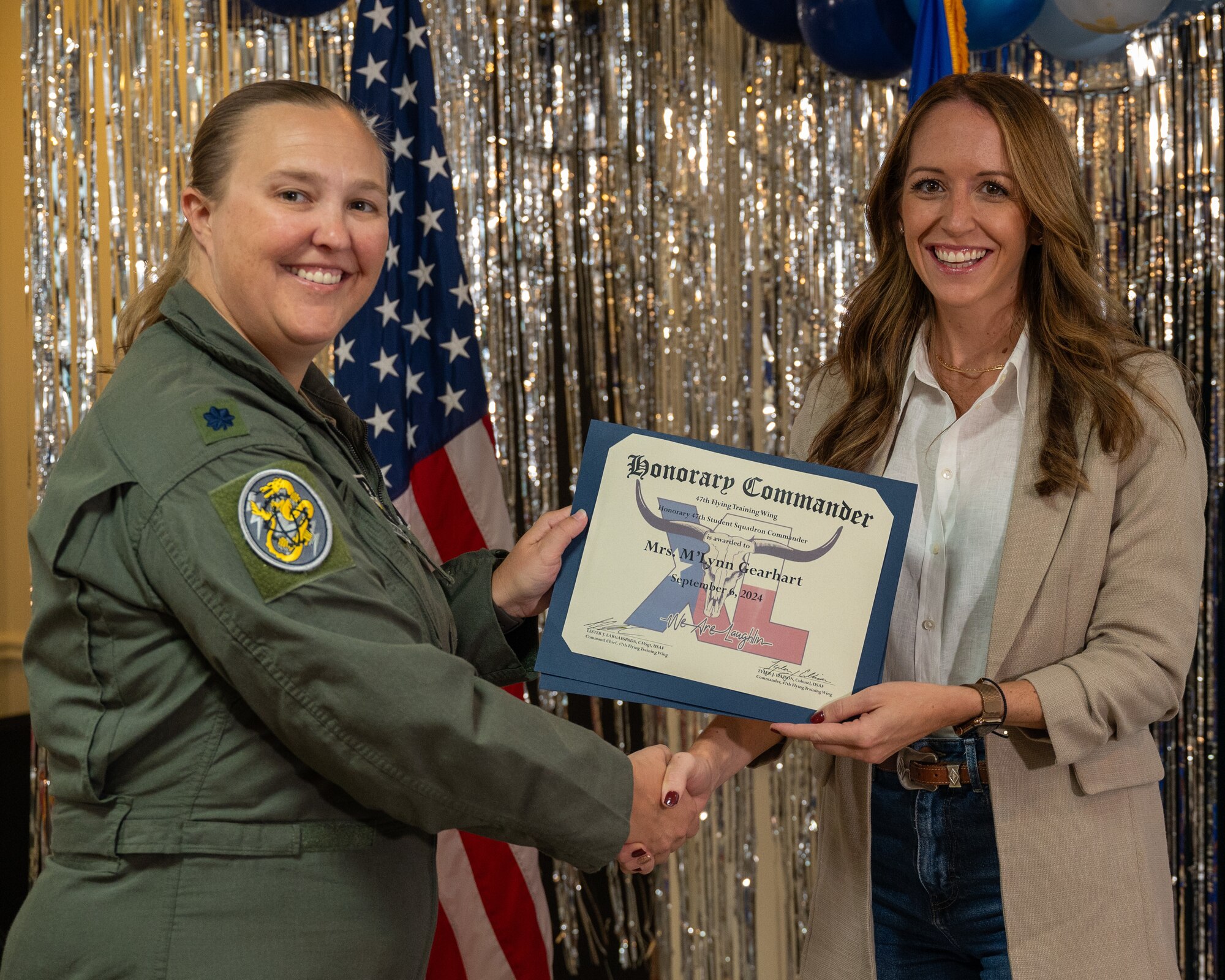 An honorary commander accepts their certificate from their commander at the honorary commander induction ceremony at Laughlin Air Force Base, Texas, Sept. 6, 2024. The honorary commander program looks to bring local community leaders and base personnel closer together, fostering the close relationship between Del Rio and Laughlin. (U.S. Air Force photo by Staff Sgt. Nicholas Larsen)