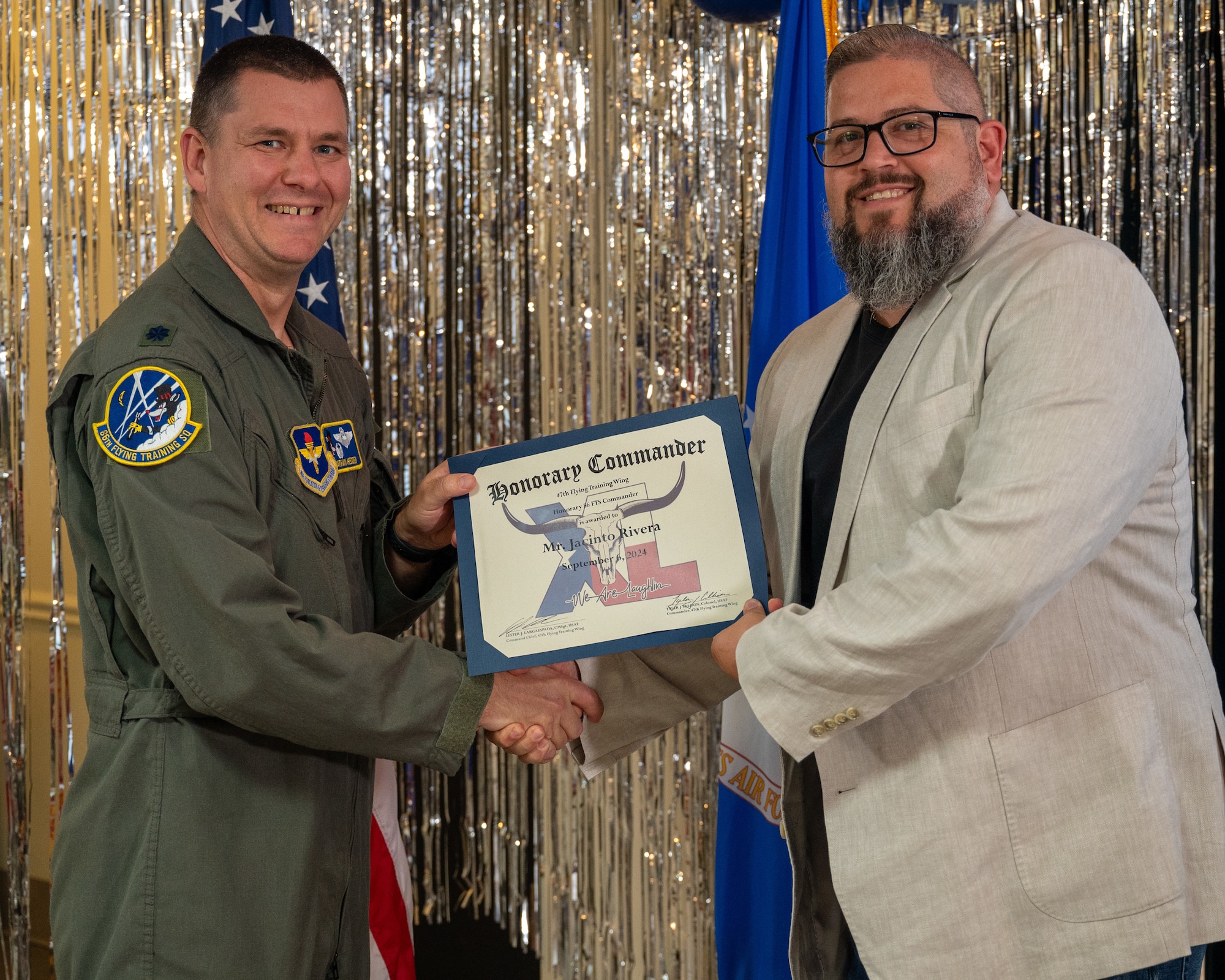 An honorary commander accepts their certificate from their commander at the honorary commander induction ceremony at Laughlin Air Force Base, Texas, Sept. 6, 2024. The honorary commander program looks to bring local community leaders and base personnel closer together, fostering the close relationship between Del Rio and Laughlin. (U.S. Air Force photo by Staff Sgt. Nicholas Larsen)