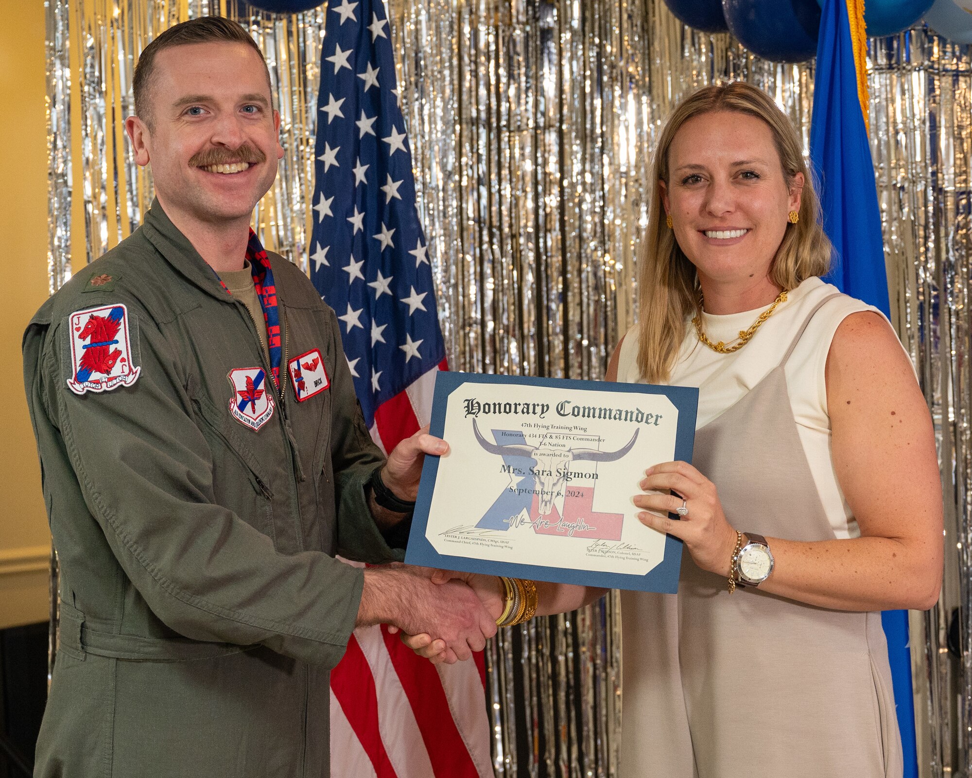 An honorary commander accepts their certificate from their commander at the honorary commander induction ceremony at Laughlin Air Force Base, Texas, Sept. 6, 2024. The honorary commander program looks to bring local community leaders and base personnel closer together, fostering the close relationship between Del Rio and Laughlin. (U.S. Air Force photo by Staff Sgt. Nicholas Larsen)