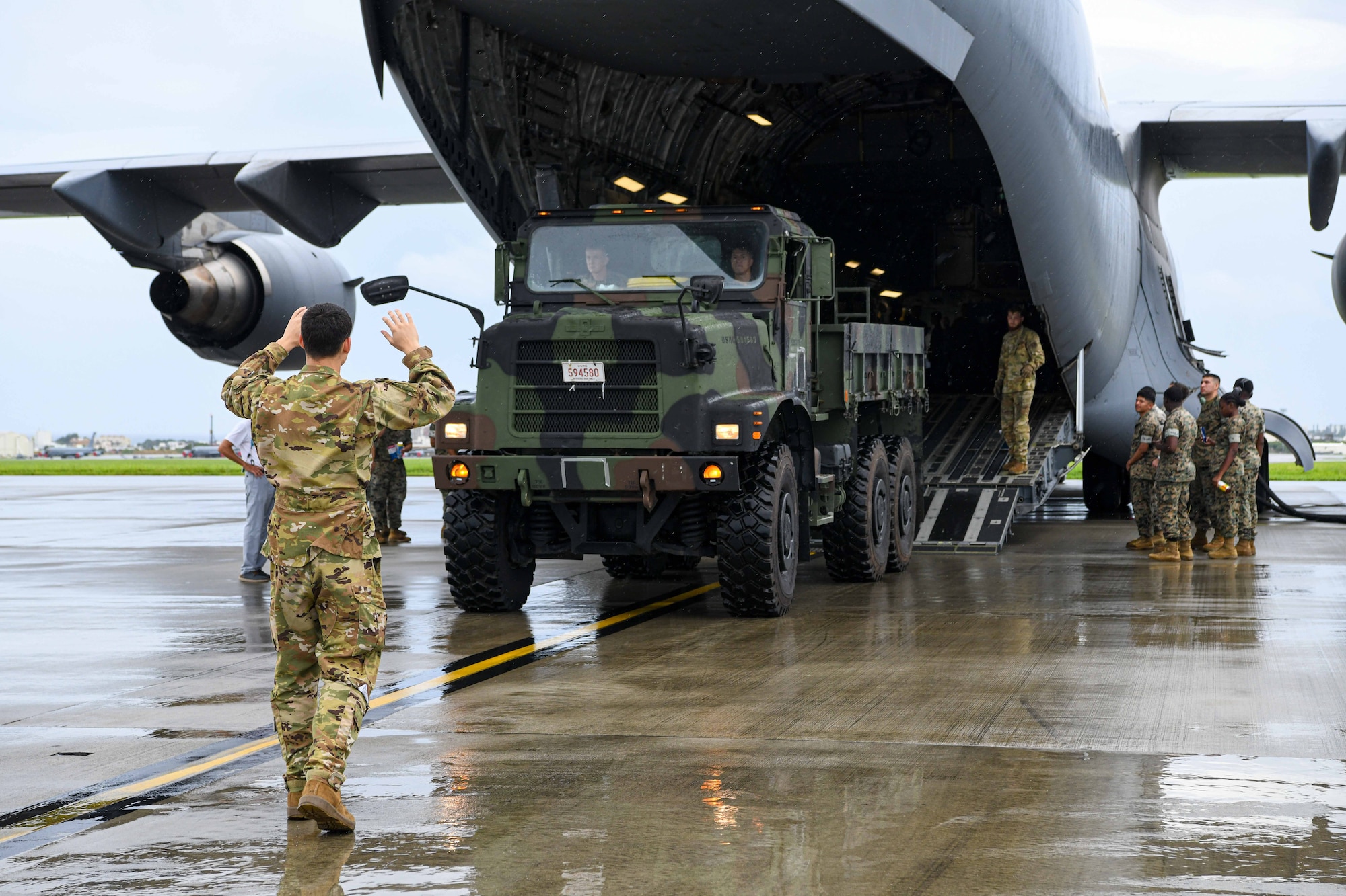 A loadmaster marshals a medium tactical vehicle replacement onto a C-17 Globemaster III.