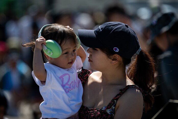 A child plays with her ear protections while being held by her mother during Misawa Air Fest at Misawa Air Base, Japan, Sept. 8, 2024.