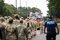 Airmen march in formation behind a firetruck