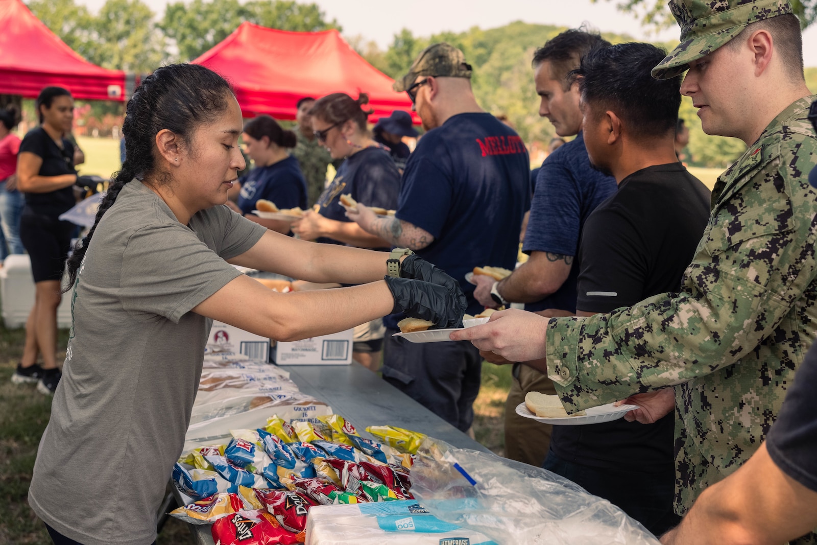 U.S. Navy Personnel Specialist Second Class Heydy Iparraguirre with Directorate for Administration, Navy Medicine Readiness and Training Command Quantico, serves food during a field meet at Lejeune Field on Marine Corps Base Quantico, Virginia, Aug. 29, 2024. The field meet took place to help build comradery and better the relations amongst the local Branch Health Clinics. (U.S. Marine Corps photo by Cpl. Darien Wright)