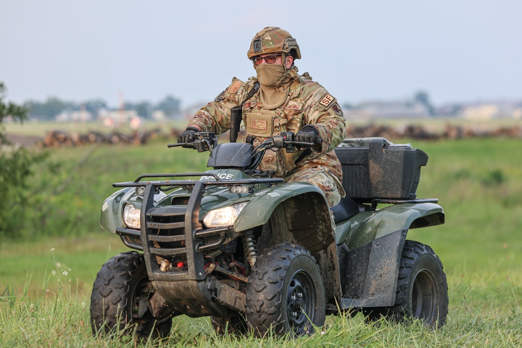 Airman riding all terrain vehicle in camouflage uniform.