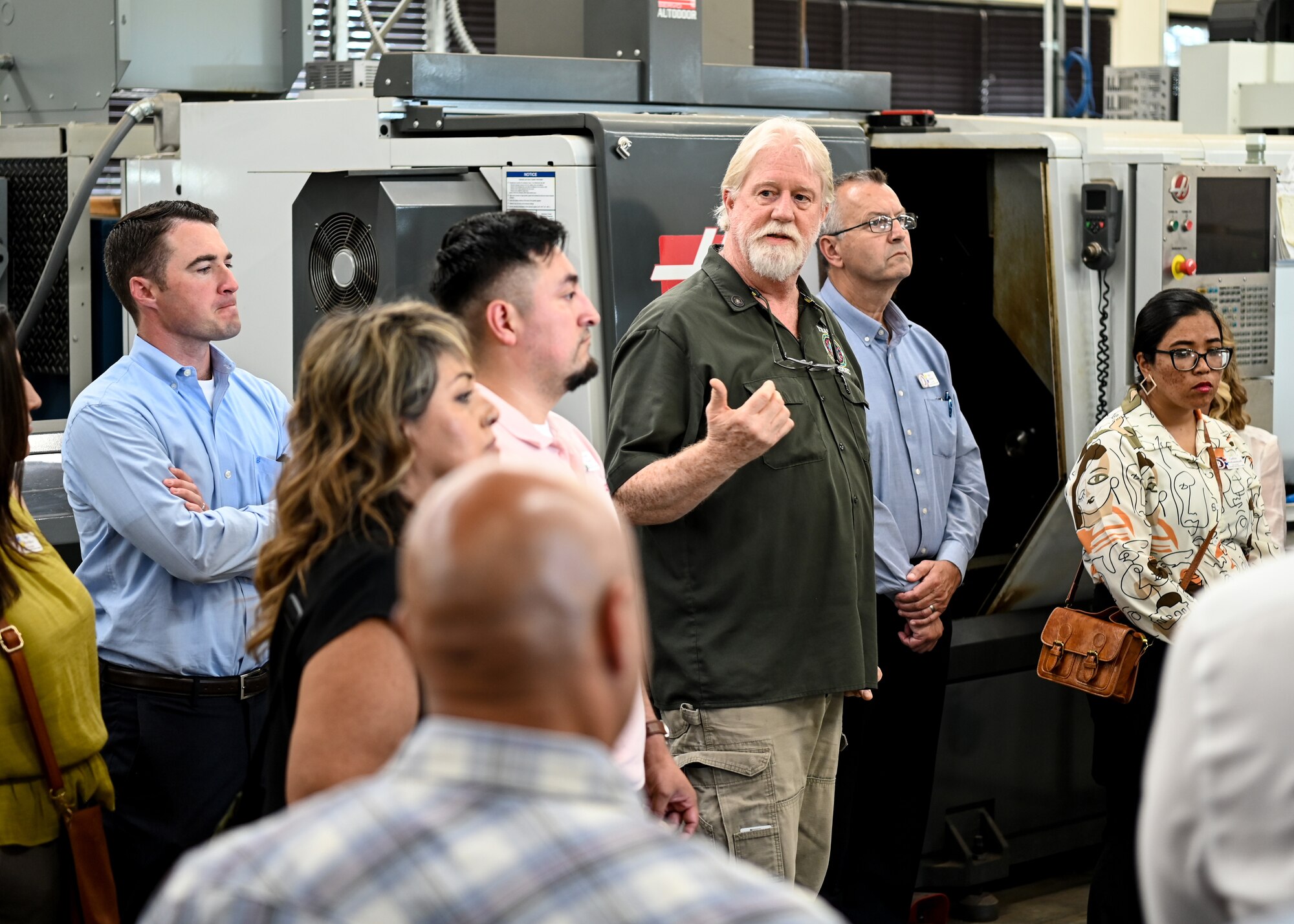 A Training Device Design and Engineering Center (TDDEC) Aerospace engineering technician explains how the surrounding machinery operates to the Leadership Santa Maria Valley members during a tour at Vandenberg Space Force Base.