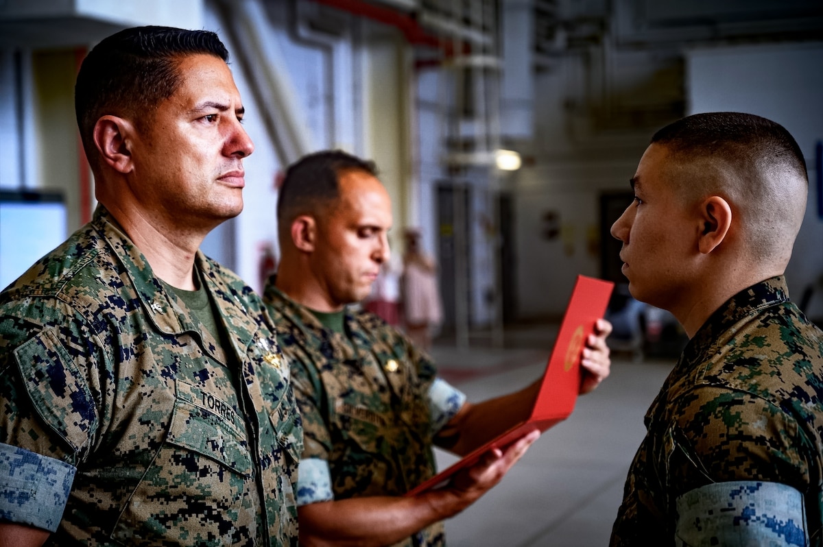 U.S. Marine Corps Col. Pablo Torres, Marine Aircraft Group 49 commanding officer, and Sgt. Andrew Gomez, MAG 49 aviation supply specialist, stand at attention during an award ceremony at Joint Base McGuire-Dix-Lakehurst, N.J., Aug. 14, 2024. Gomez received the Navy and Marine Corps Medal for extricating a passenger from a burning vehicle on June 19, 2023. (U.S. Air Force photo by Senior Airman Matt Porter)