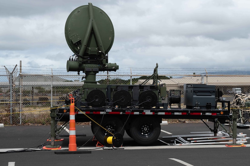 A satellite system sits on a mobile platform in a parking area.