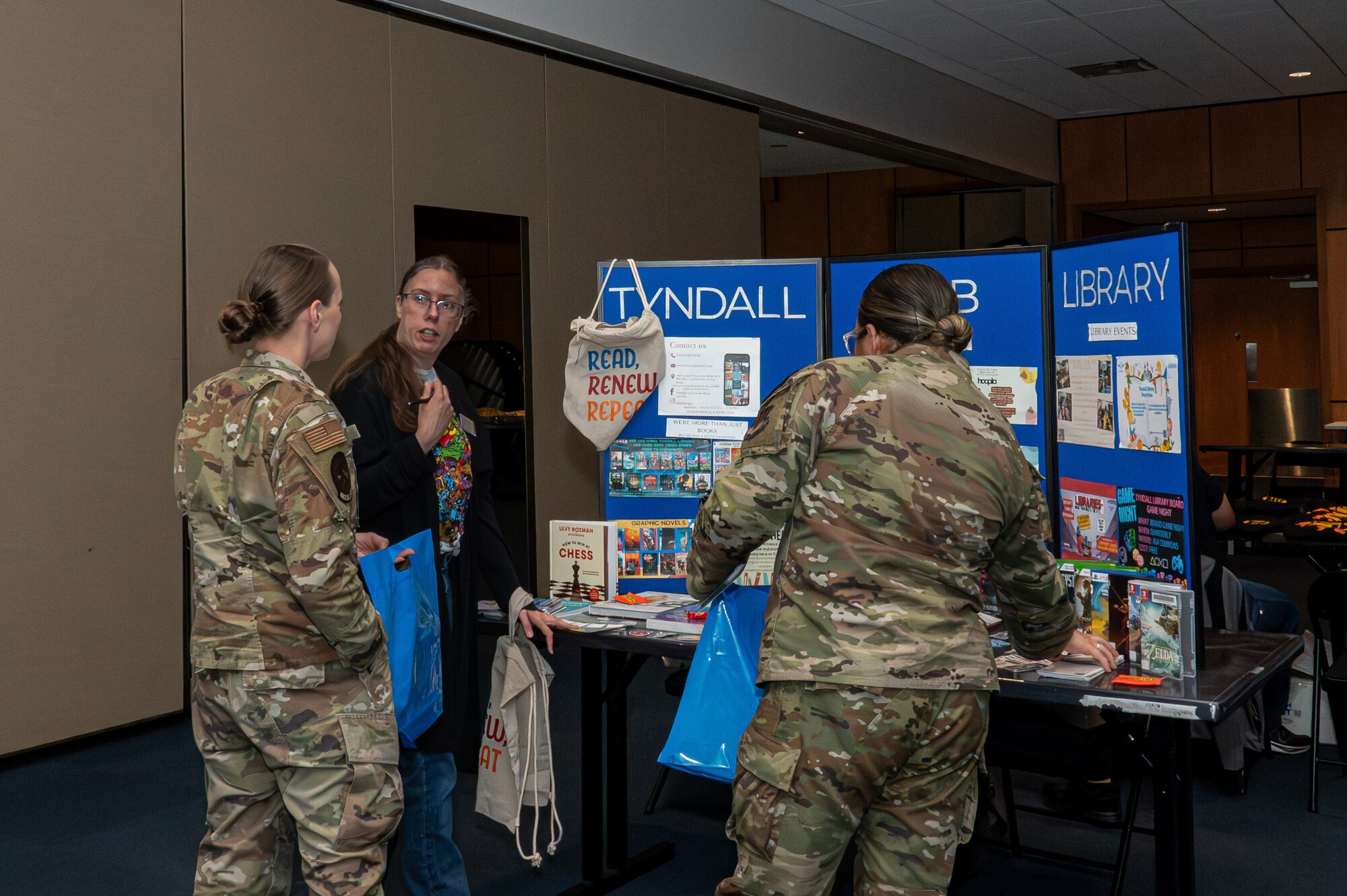 U.S. Airmen talk with an organization member from Tyndall Library at Tyndall Air Force Base