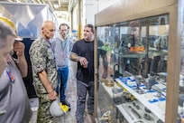 Handsome Barton, additive manufacturing mechanic, Shop 31, Inside Machinist, shows Rear Adm. Todd Weeks, program executive officer, Strategic Submarines, a variety of 3D-printed parts created by shipyard employees July 16, 2024, during a tour of Puget Sound Naval Shipyard & Intermediate Maintenance Facility in Bremerton, Washington. (U.S Navy photo by Jeb Fach)