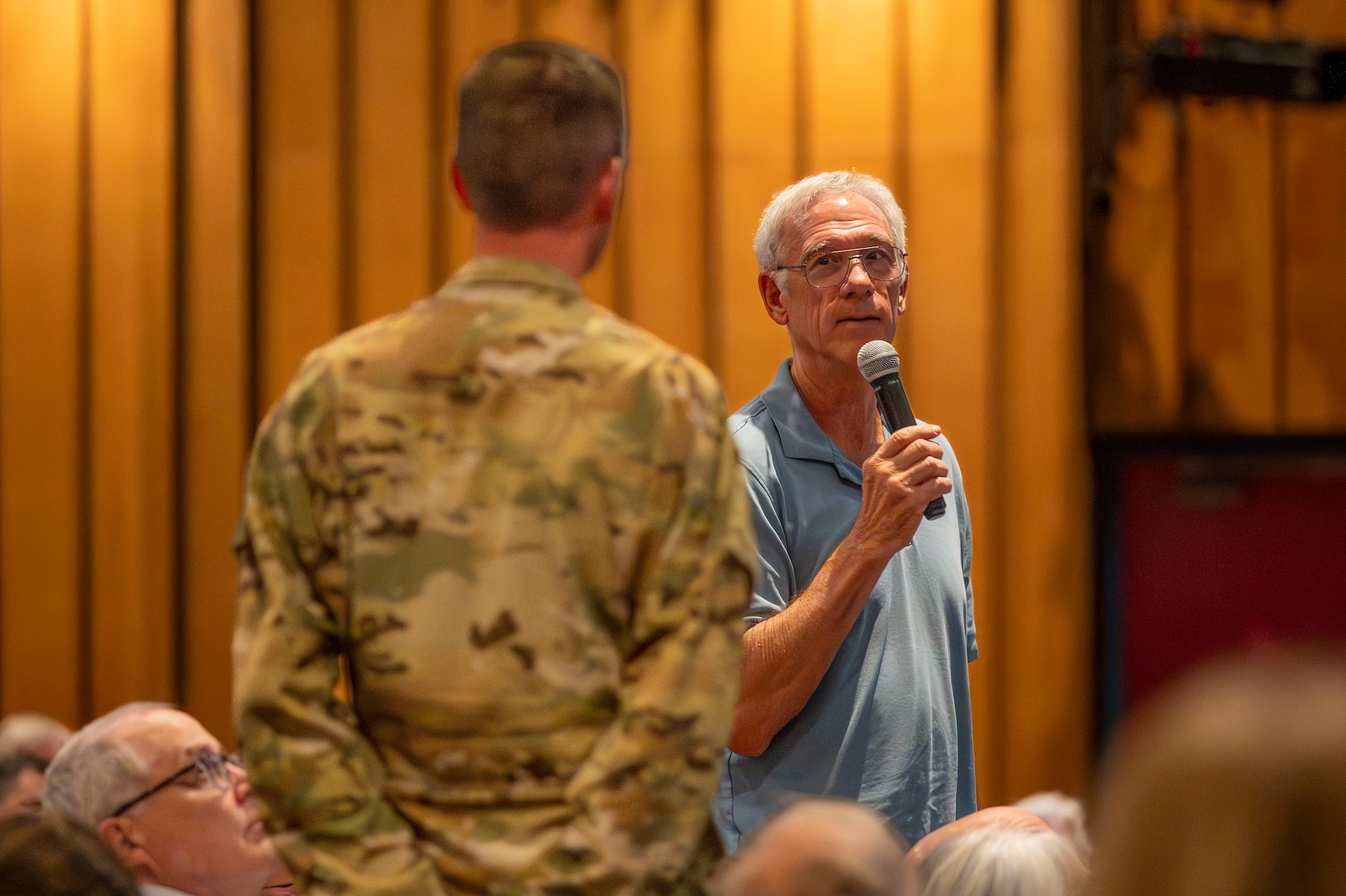 A man standing up with a microphone in his hand and looking at a man in a military uniform.