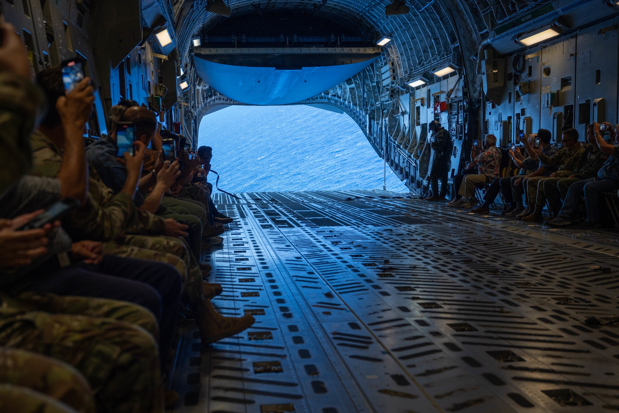 Airmen and civilians fly in a military aircraft.