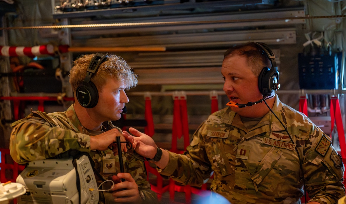 Capt. David Harrow discusses medical care with Staff Sgt. Eric Hannah while on an HC-130J Combat King II aircraft