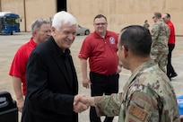 Airman, right, shakes hands with delegates retired U.S. Air Force Lt. Gen. Leon Scott Rice.