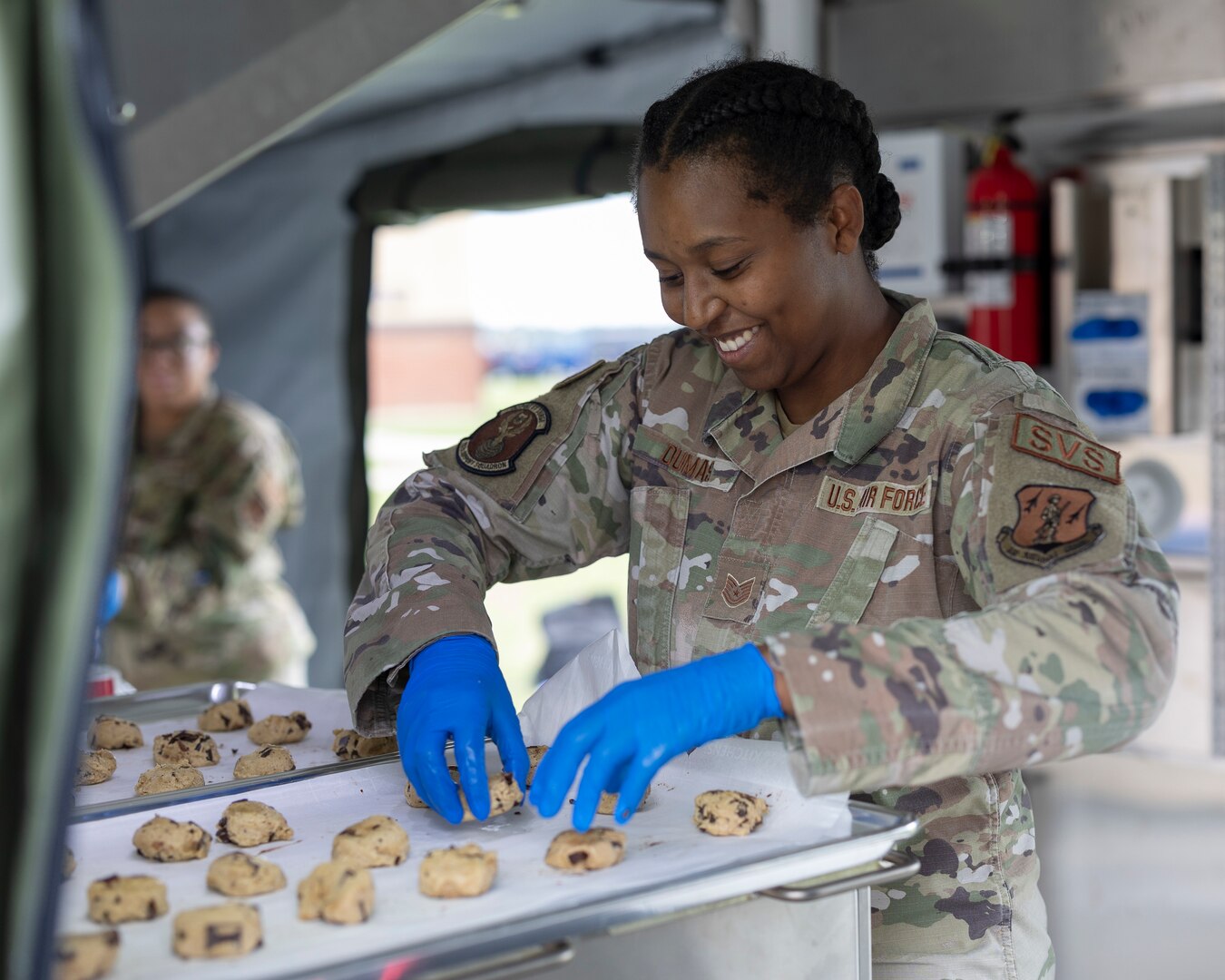 Airman places cookie dough on cookie sheet