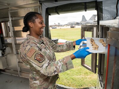 Airman puts tray of cookie dough into the oven