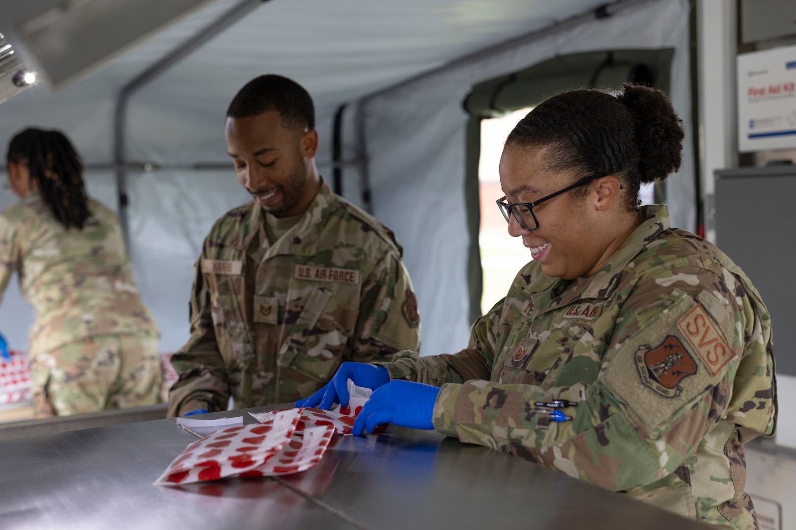 Two Airman put cookies in individual bags