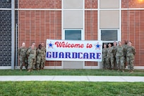 U.S. Air Force medical technicians assigned to the Ohio National Guard’s 180th Fighter Wing pose for a photo in front of sign advertising Guard Care in Xenia, Ohio, Aug. 11, 2024. Guard members helped provide free health care to more than 1,000 people while honing their skills.