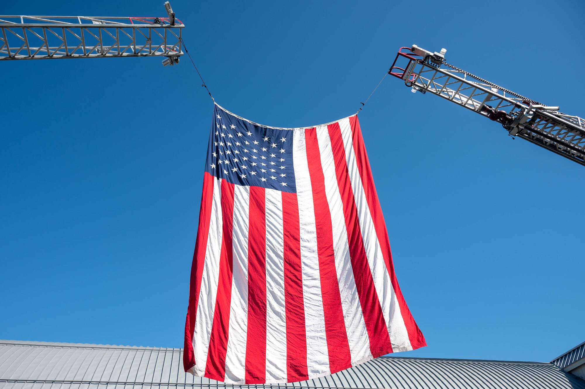 An American flag hangs between the ladders of fire trucks belonging to the Dover Air Force Base Fire Department and the city of Dover during the 23rd Anniversary 9/11 Memorial Service at the Air Mobility Command Museum on Dover AFB, Delaware, Sept. 11, 2024. The memorial service honored the civilian casualties of the terrorist attack as well as the police officers, firefighters and emergency first responders that lost their lives attempting to save them. (U.S. Air Force photo by Mauricio Campino)