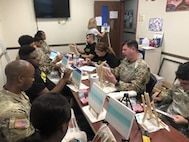 Spc Dominique Washington, just under the TV screen, watches art instruction from Teresa Kramer