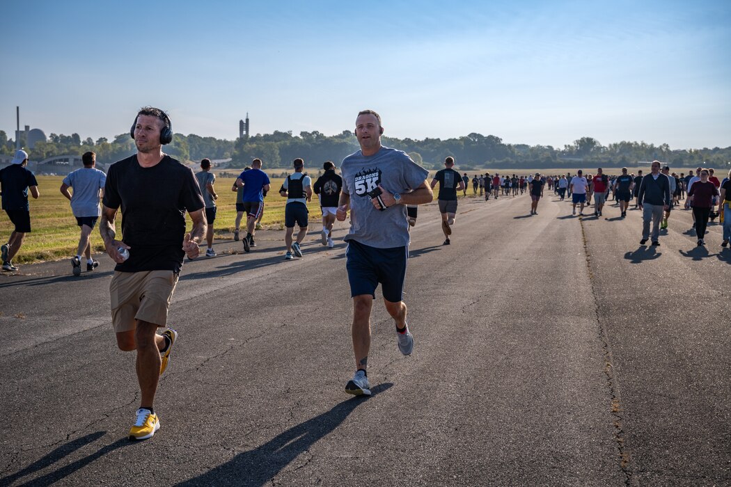 Two runners moving forward as a large group of runners and walkers appear in the background going the other direction