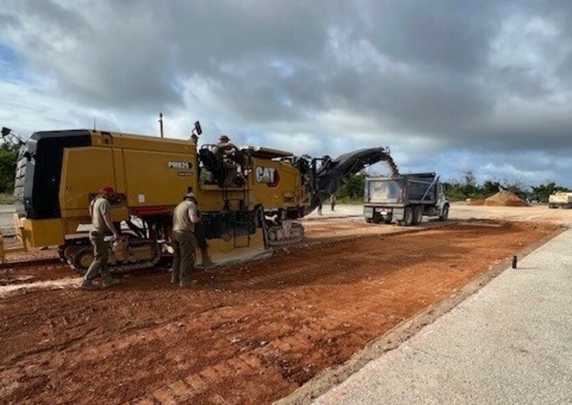 Military members operate heavy machinery equipment to excavate a portion of runway.
