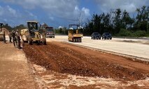 Military members operate heavy machinery equipment to excavate a portion of runway.