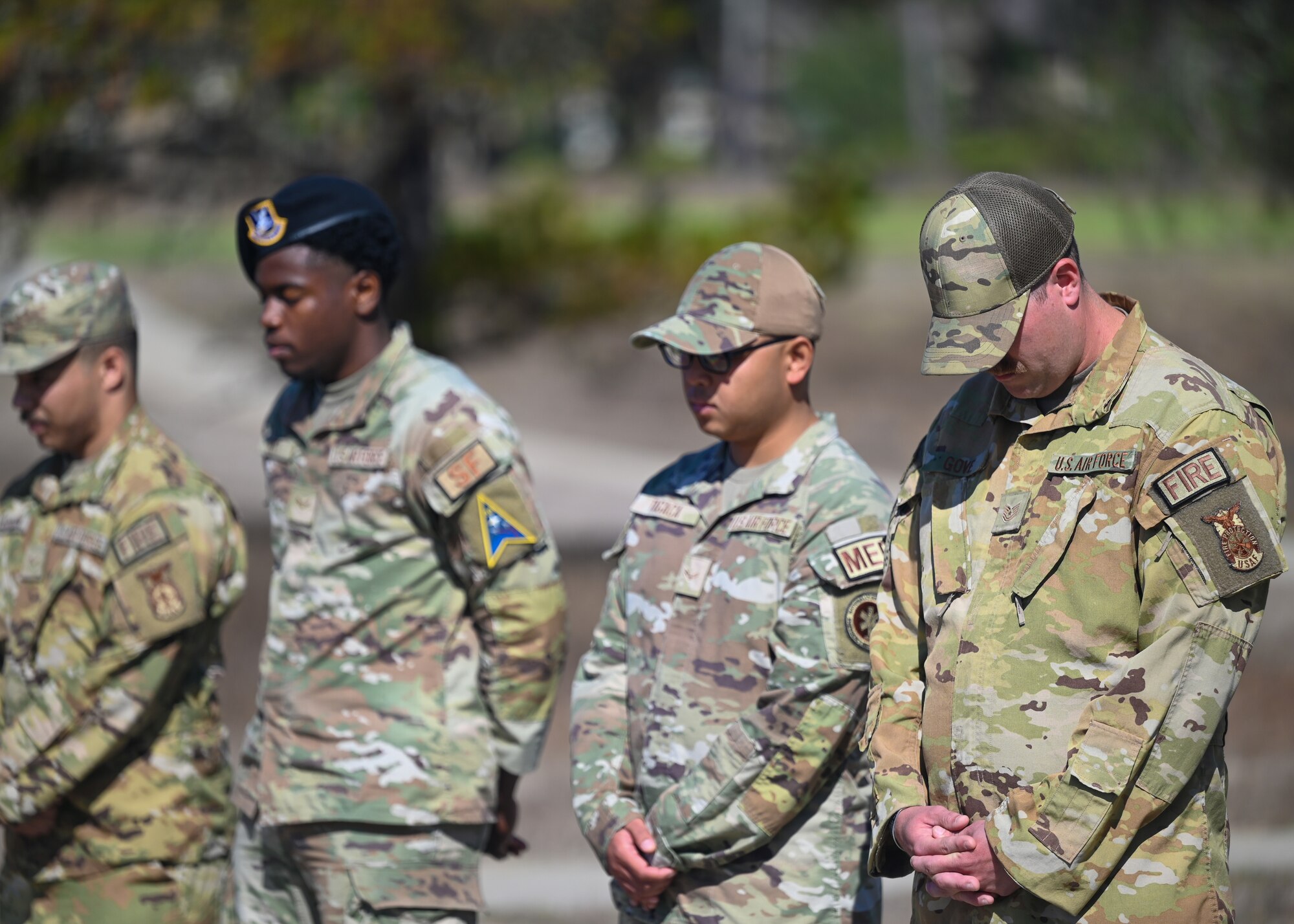 Men in uniform bow their heads in prayer and reflection during a 9/11 remembrance ceremony.