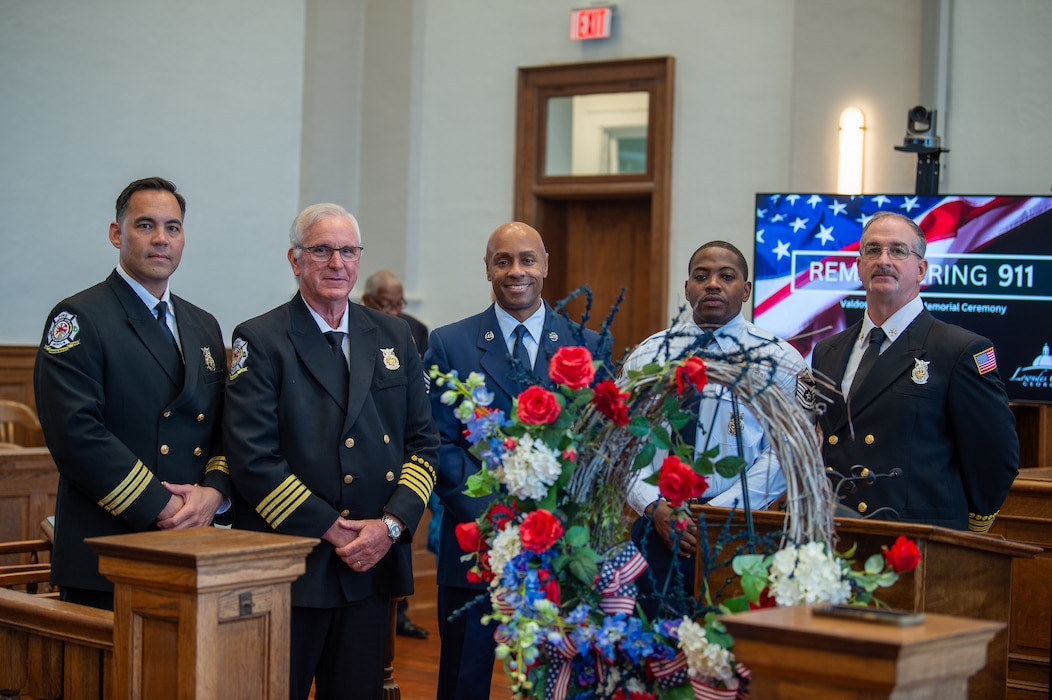 Members of the Team Moody Firehouse pose for a picture with the 9/11 Memorial Wreath at Lowndes County Courthouse, Valdosta, Georgia, Sept. 11, 2024. The members from Team Moody represented our base and showed support to the local community by attending the event. (U.S. Air Force photo by Airman 1st Class Iain Stanley)