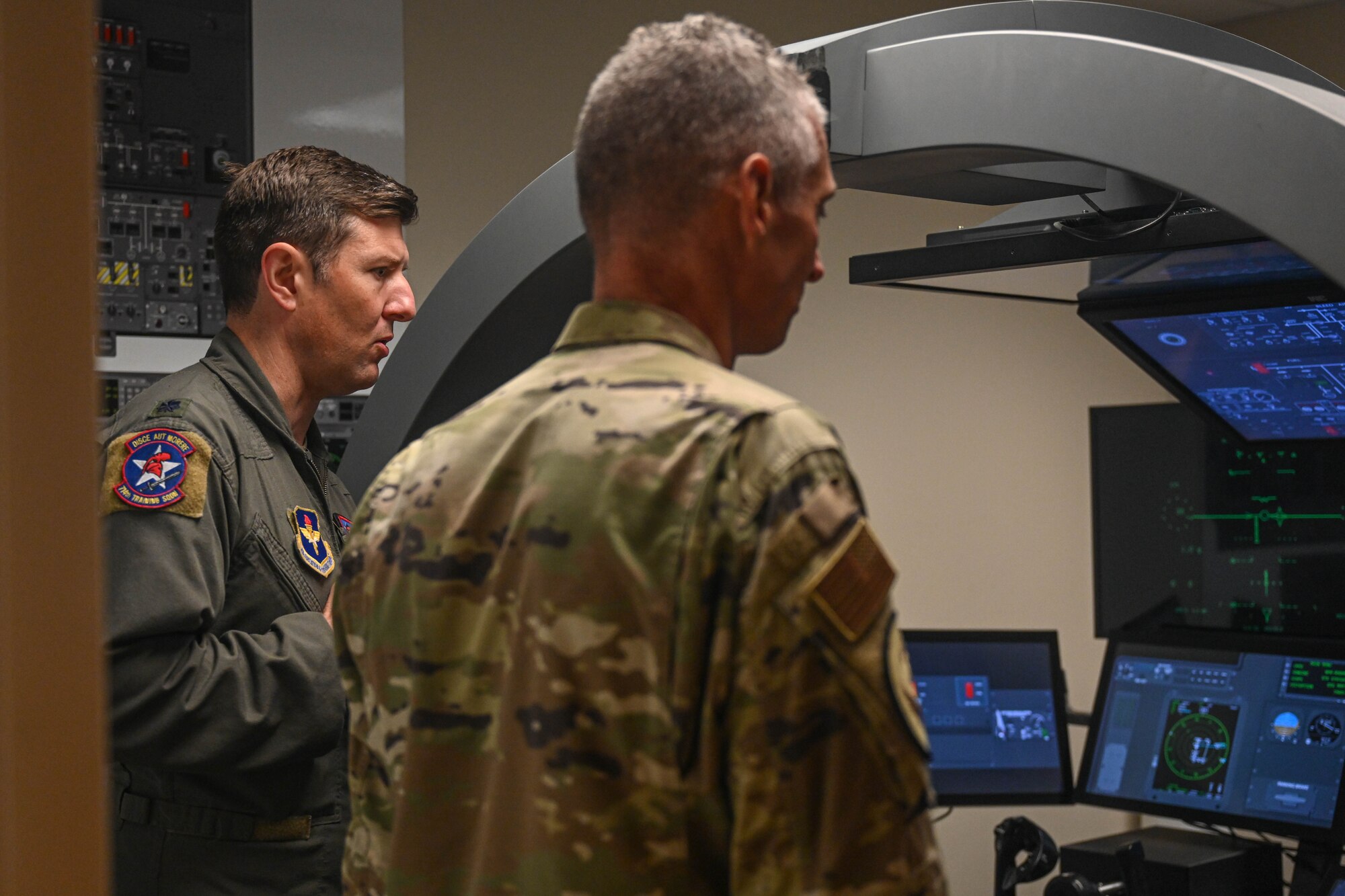 Airmen look at a training simulator.