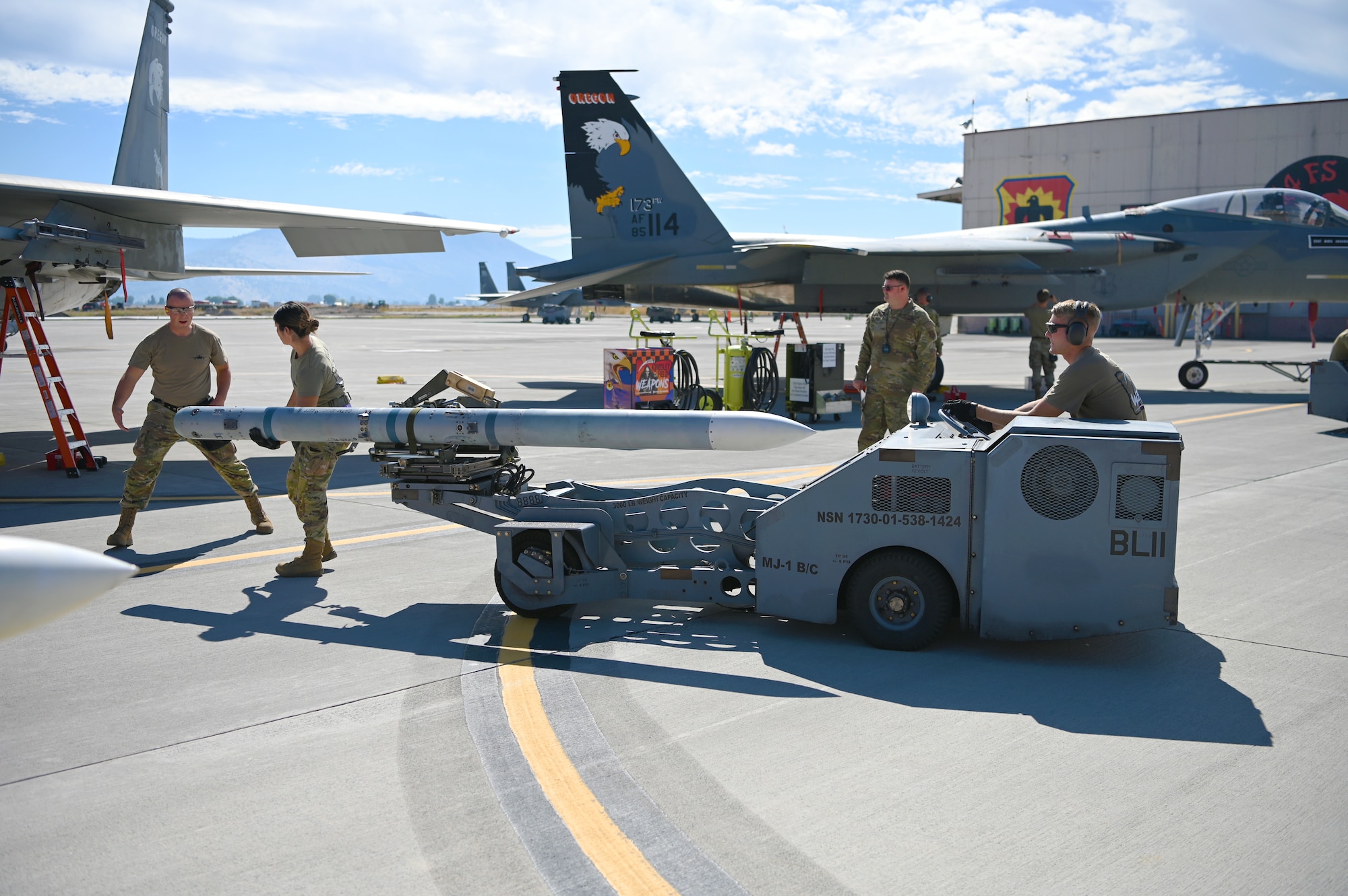 U.S. Air Force Airmen with the 173rd Fighter Wing Aircraft Maintenance Squadron weapons load crew team use an MJU-1 jammer to load a missile onto a F-15C Eagle.