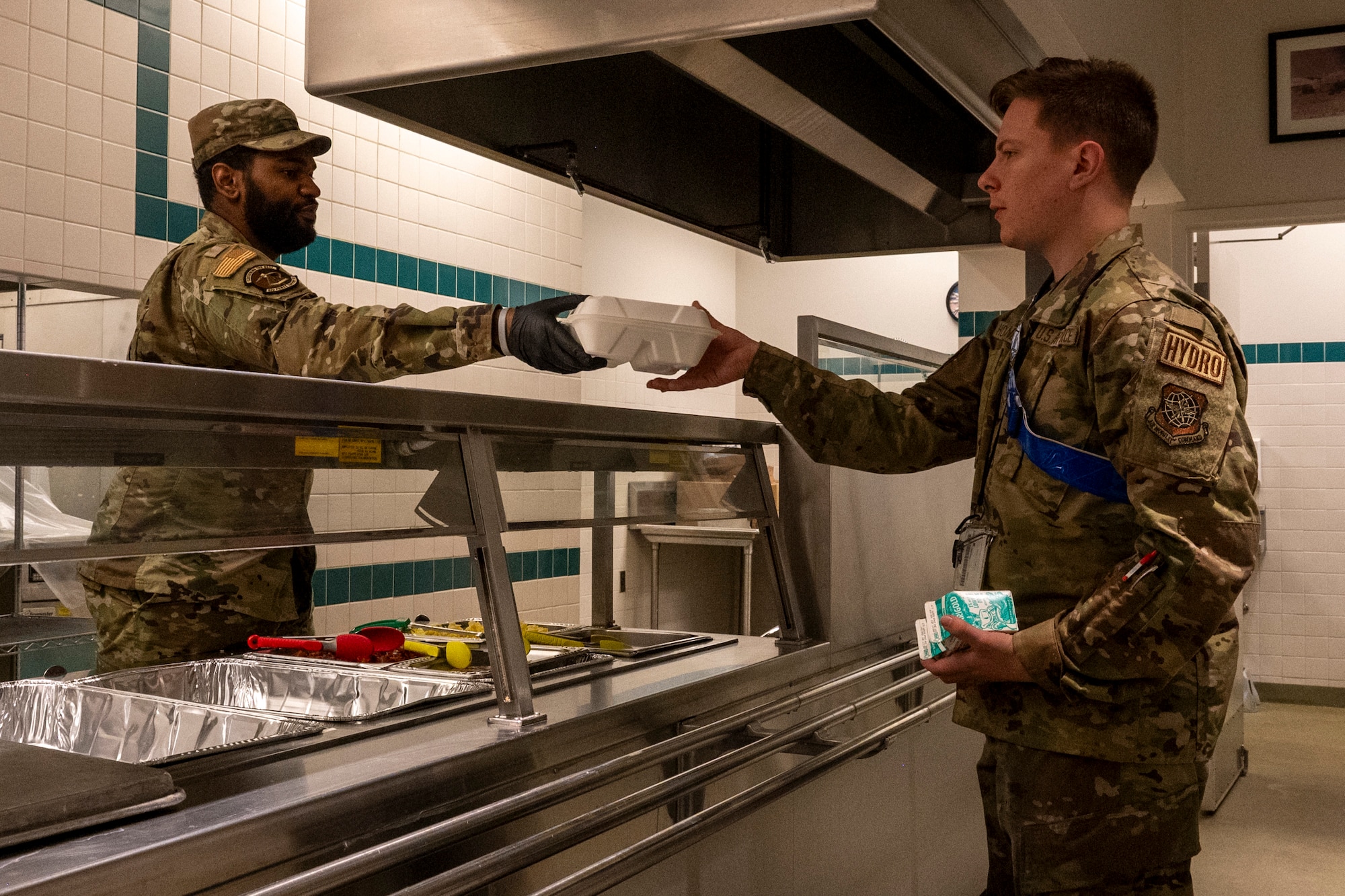 Senior Airman Mackenzie Lemon, left, a services specialist assigned to the 92nd Force Support Squadron, hands a container of food to Airman 1st Class Evan Holzknecht, a hydraulic systems technician assigned to the 92nd Maintenance Squadron, during exercise Titan Fury 24-7 at Fairchild Air Force Base, Washington, Sept. 11, 2024. Lemon and the 92nd FSS provided hot meals to aircrews on 24-hour standby. Titan Fury is a recurring total force exercise that ensures Fairchild’s Airmen are trained and ready to provide Rapid Global Mobility at a moment’s notice in support of strategic deterrence and the National Defense Strategy. This exercise is an example of how the 92nd Air Refueling Wing is engaged, postured and ready with a credible force to assure, deter and defend in an increasingly complex security environment. (U.S. Air Force Photo by Airman 1st Class Matthew Arachikavitz)