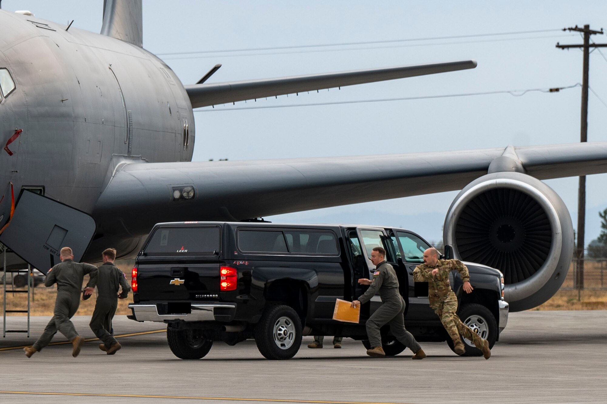 Airmen run to a jet on the flightline.
