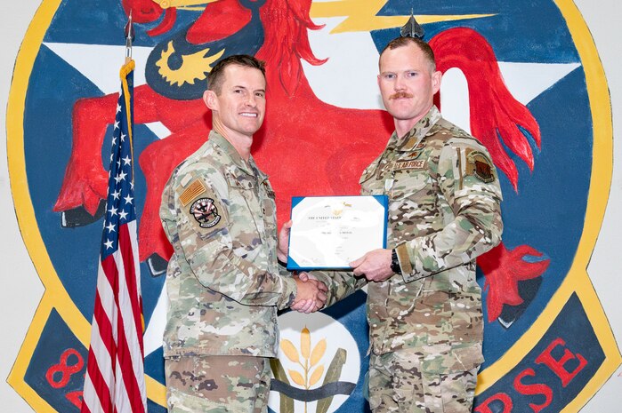 Two men holding a certificate posing for a photo