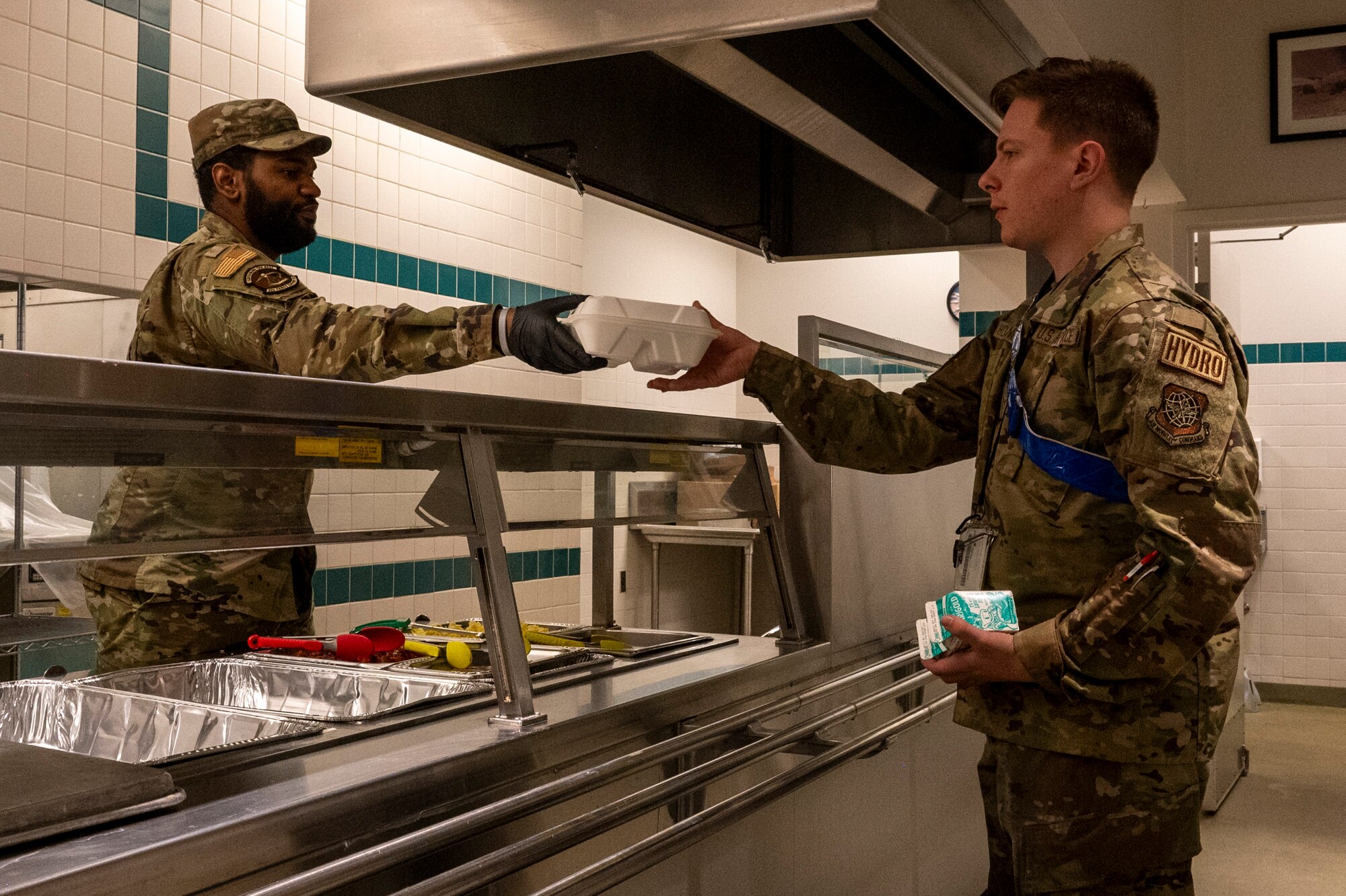 Senior Airman Mackenzie Lemon, left, a services specialist assigned to the 92nd Force Support Squadron, hands a container of food to Airman 1st Class Evan Holzknecht, a hydraulic systems technician assigned to the 92nd Maintenance Squadron, during exercise Titan Fury 24-7 at Fairchild Air Force Base, Washington, Sept. 11, 2024. Lemon and the 92nd FSS provided hot meals to aircrews on 24-hour standby. Titan Fury is a recurring total force exercise that ensures Fairchild’s Airmen are trained and ready to provide Rapid Global Mobility at a moment’s notice in support of strategic deterrence and the National Defense Strategy. This exercise is an example of how the 92nd Air Refueling Wing is engaged, postured and ready with a credible force to assure, deter and defend in an increasingly complex security environment. (U.S. Air Force Photo by Airman 1st Class Matthew Arachikavitz)