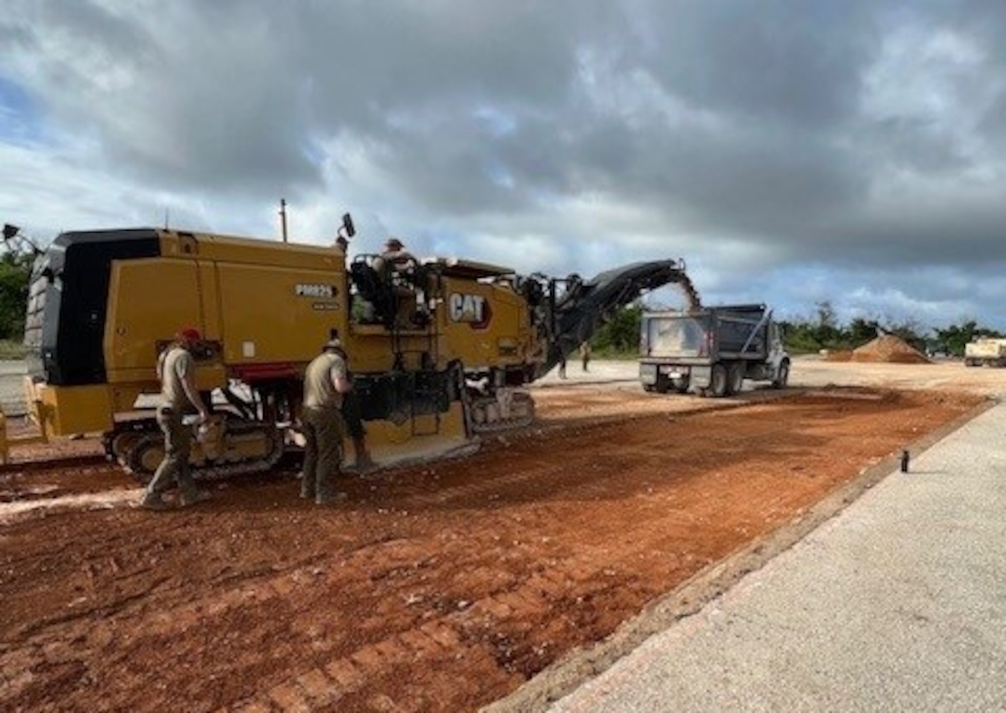 Military members operate heavy machinery equipment to excavate a portion of runway.