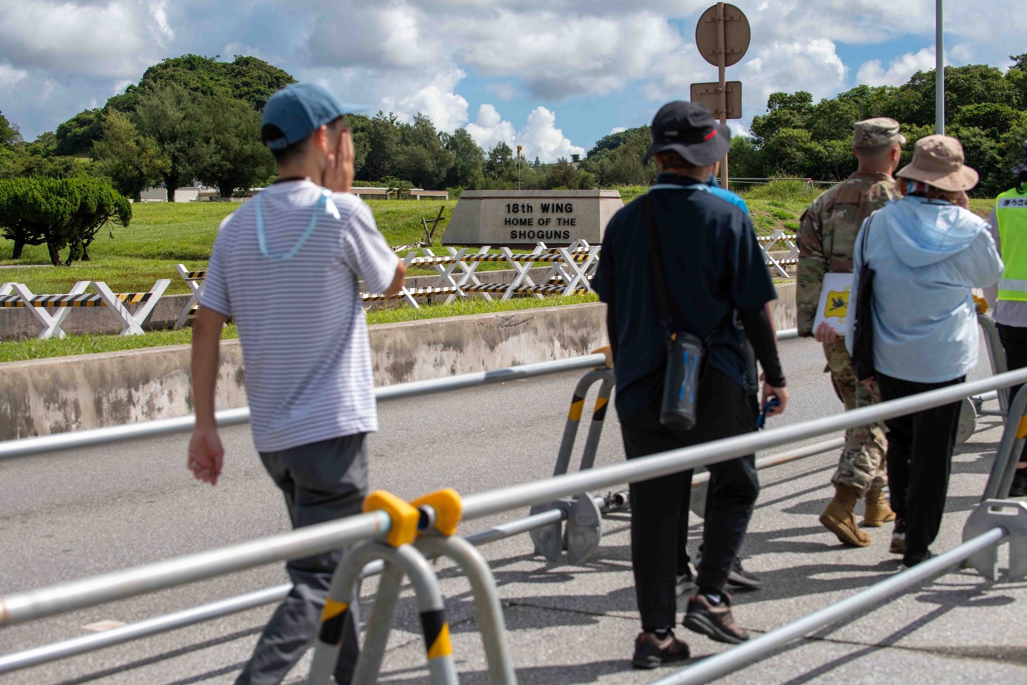 Japanese locals walk past the front of the 18th Wing sign