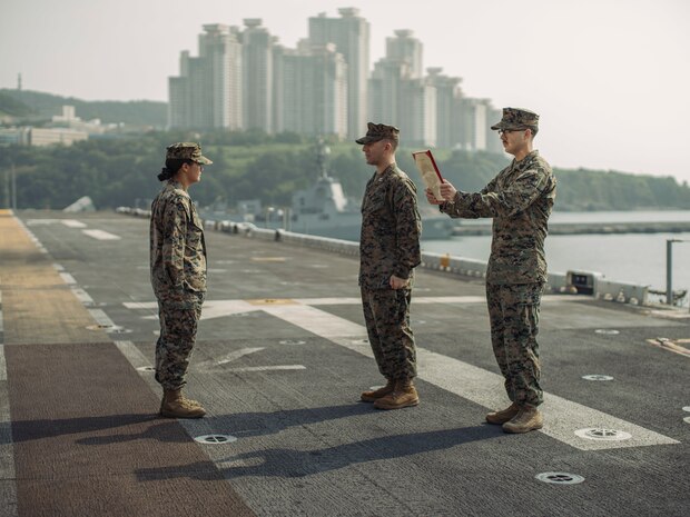 Marine Corps Gunnery Sgt. Donald Holbert, the communication strategy and operations staff noncommissioned officer in charge of the 15th Marine Expeditionary Unit, read a promotion warrant for Sgt. Amelia Kang, a combat graphics specialist, aboard the amphibious assault ship USS Boxer (LHD 4) at Busan Naval Base, South Korea, Sept. 8, 2024. The 15th MEU conducted Exercise Ssang Yong 24 to strengthen the Republic of Korea-U.S. Alliance through joint training, contributing toward combined amphibious capability.