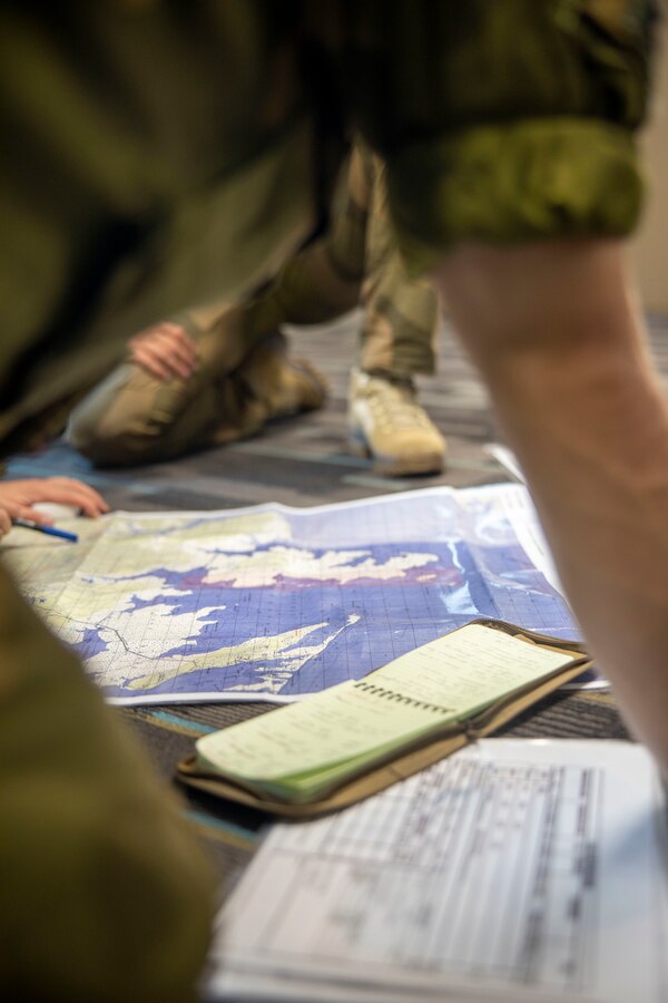 NATO allied service members plot points on a map during exercise Burmese Chase 24 at Marine Corps Base Camp Lejeune, North Carolina, Sept. 5, 2024. Burmese Chase is an annual U.S. led, multi-lateral exercise that includes training on integration of ground and air fires, infantry tactics and naval gunfire alongside NATO allies. (U.S. Marine Corps photo by Cpl. Jacquilyn Davis)