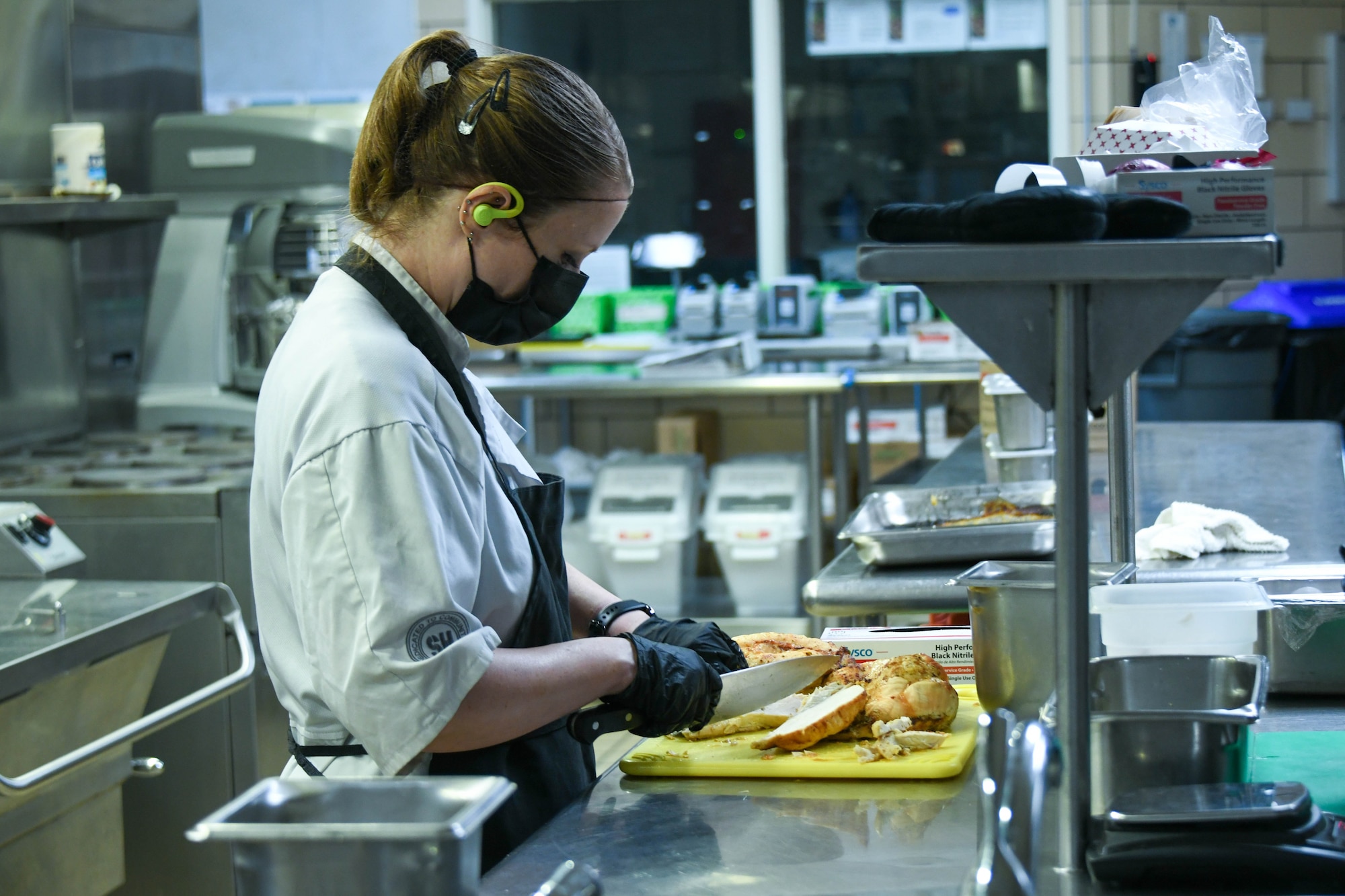 Jessica Slusser, cook, cuts chicken at Altus Air Force Base, Oklahoma, Sept. 5, 2024. The Hangar 97 dining facility rotates menus on a regular basis ensuring Airmen have a variety of balanced, nutritious options in alignment with military nutrition guidelines.  (U.S. Air Force photo by Senior Airman Miyah Gray)